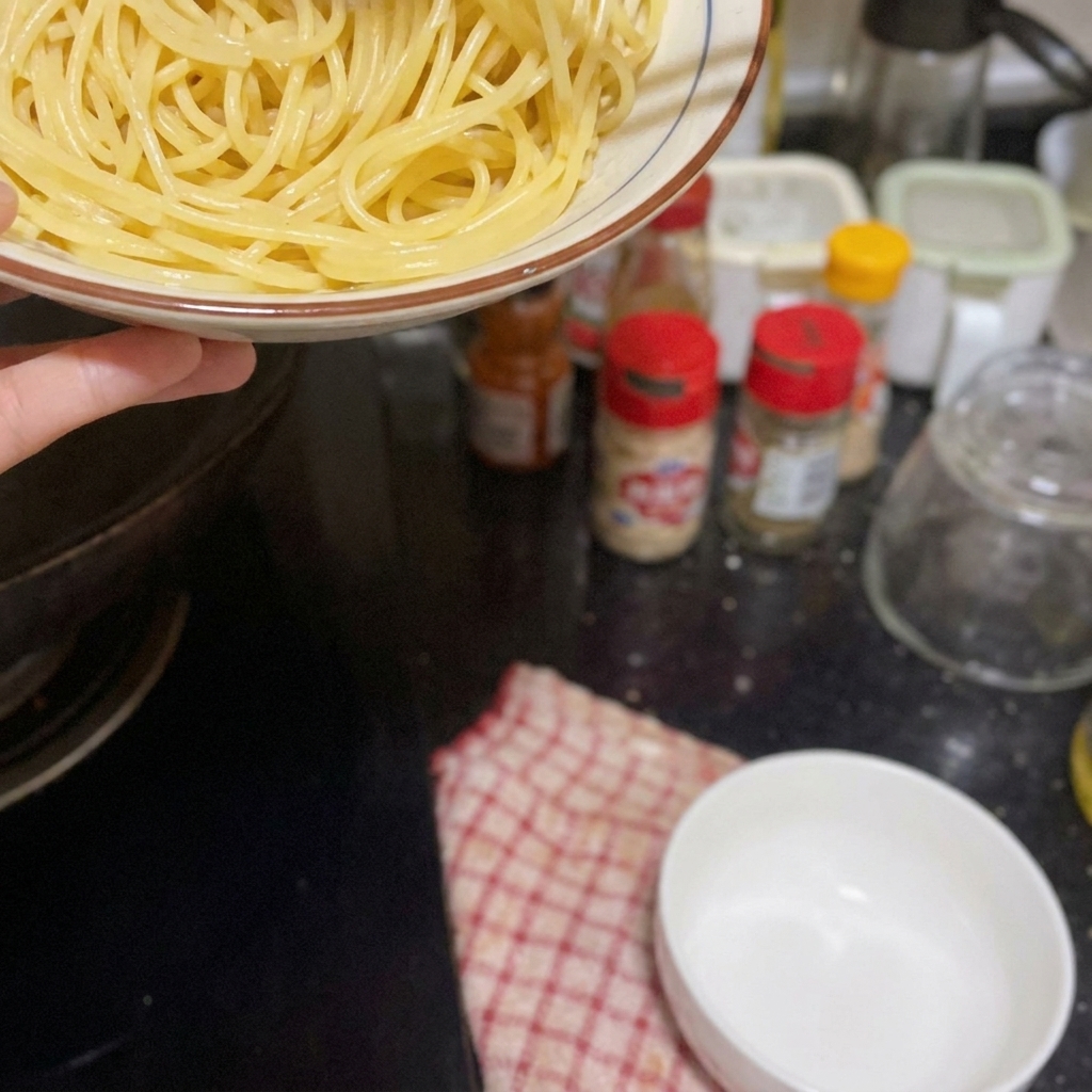 Una mano che aggiunge gli spaghetti cotti nella padella con i gamberi e il condimento.