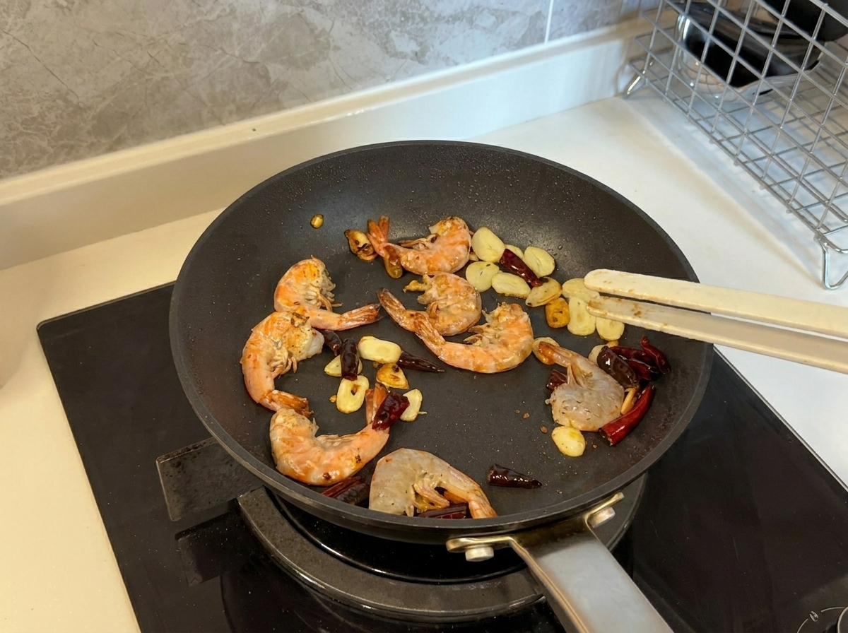 Gamberi che diventano rosa e dorati mentre vengono saltati in padella con aglio e peperoncino.