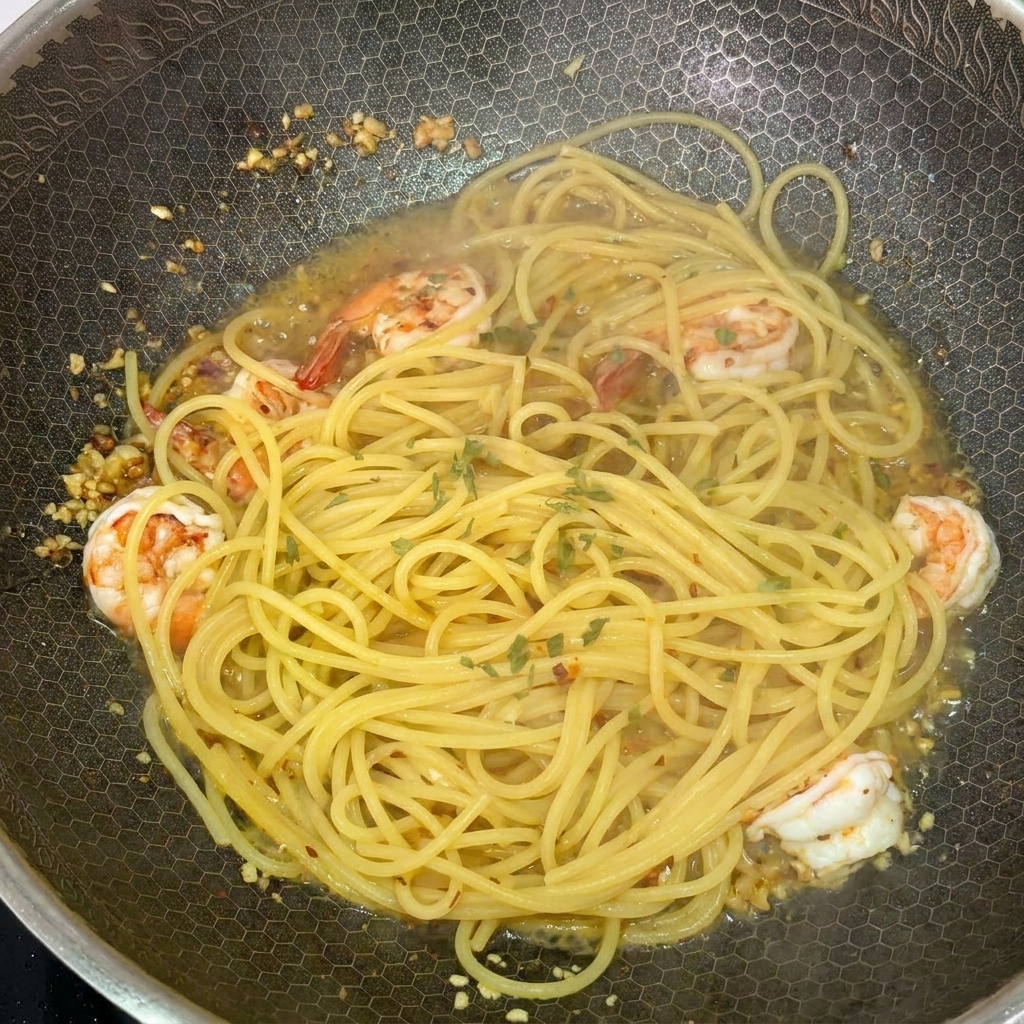 Spaghetti e gamberi nel wok fumante decorati con prezzemolo fresco tritato.