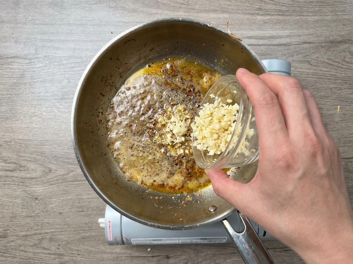 Aglio tritato versato da una ciotolina in una padella calda con burro fuso e olio.