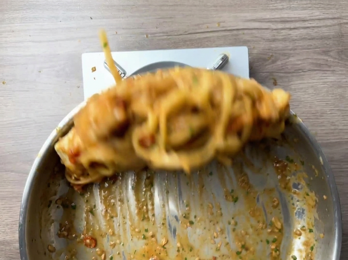 Linguine e gamberi saltati energicamente in padella, con effetto movimento.