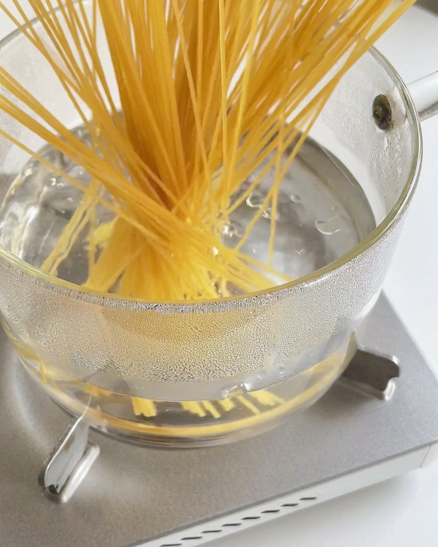 Un mazzo di spaghetti secchi immersi in una pentola dacqua bollente.
