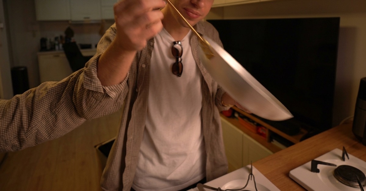 Spaghetti crudi immersi in una grande pentola di metallo piena di acqua bollente.