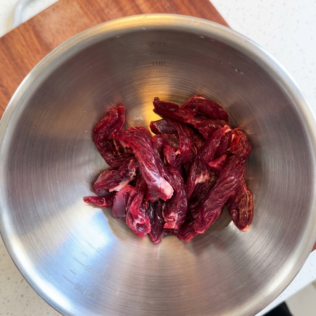 Strisce di filetto di manzo crudo in una ciotola di acciaio inox.