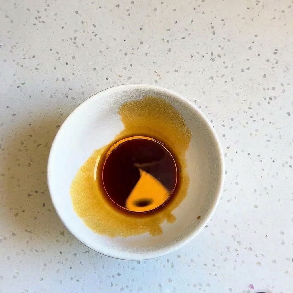 Una piccola ciotola bianca contenente una salsa scura ben miscelata.