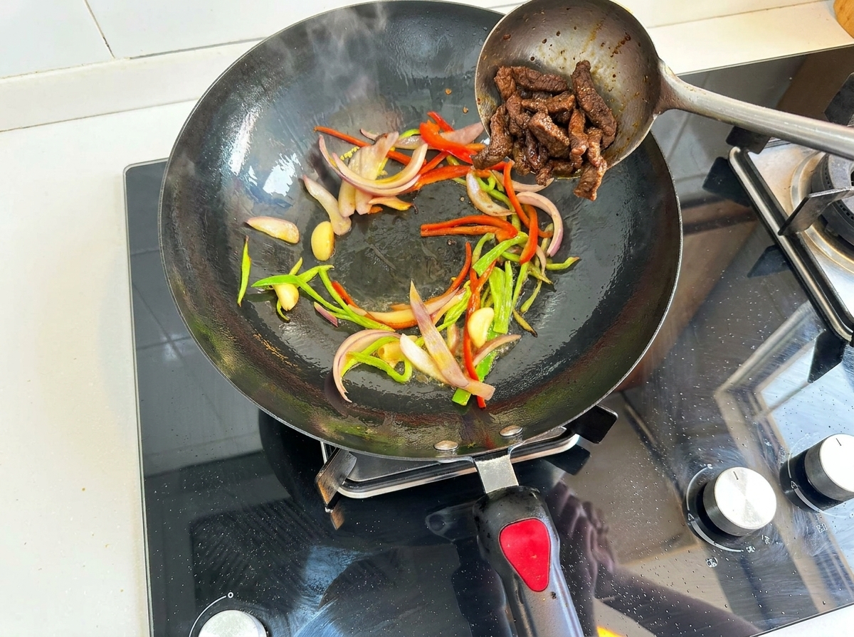 Carne di manzo aggiunta nuovamente nel wok con peperoni e cipolle.