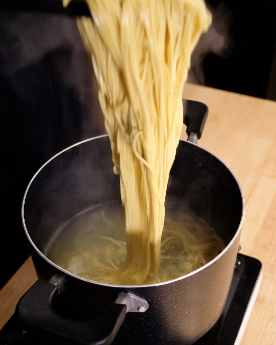Spaghetti fumanti sollevati dalla pentola dacqua bollente con una pinza da cucina.