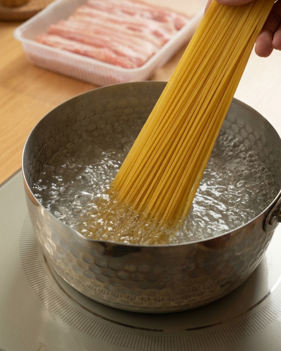 Una mano che mette gli spaghetti in una pentola con acqua in pieno bollore.
