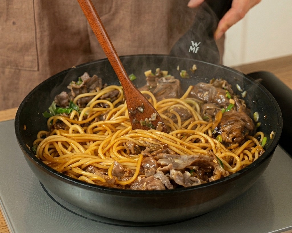 Saltare spaghetti, manzo e salsa con una spatola di legno.