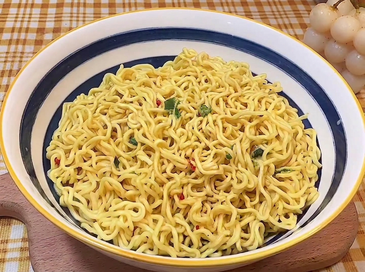 Noodles cotti disposti ordinatamente al centro di una ciotola di ceramica blu e bianca.