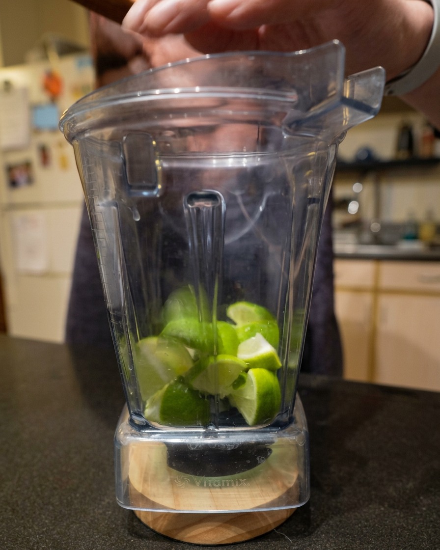 Pezzetti di lime fresco tagliati allinterno della caraffa di un frullatore.