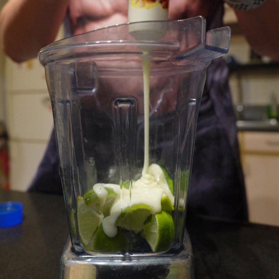 Latte condensato zuccherato versato su lime tagliati nel frullatore.