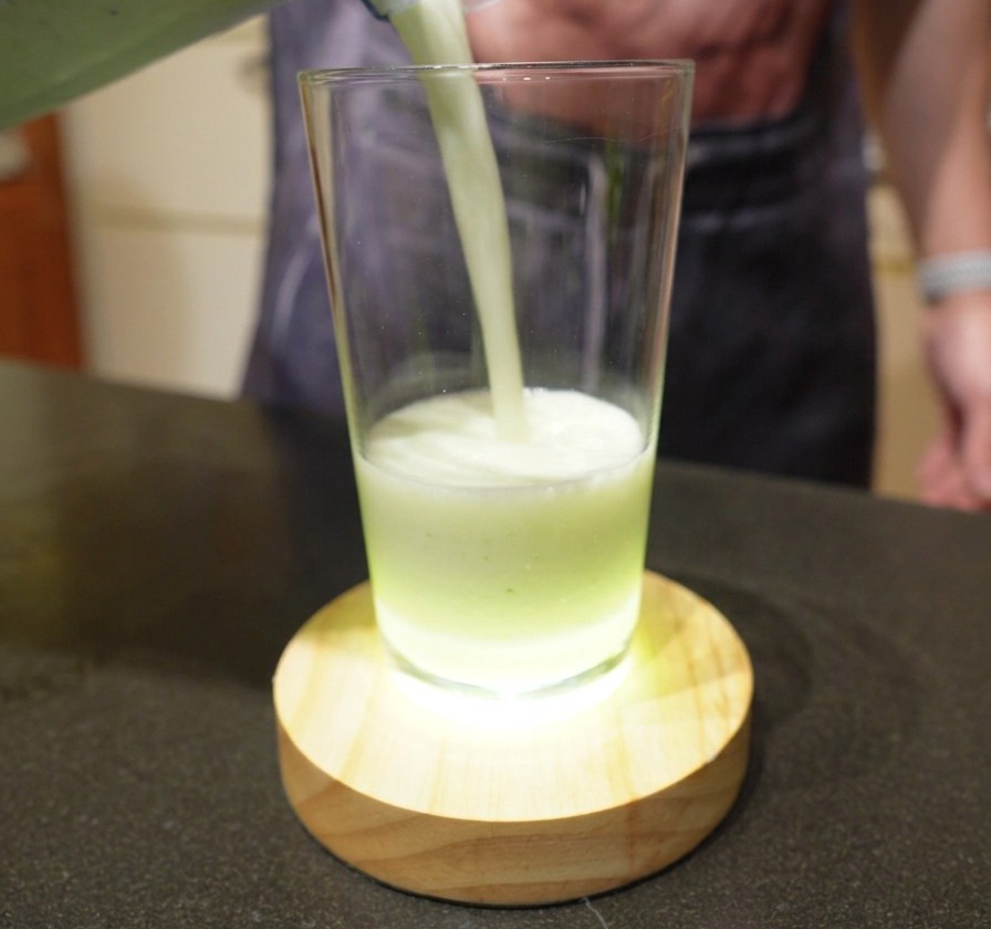 Limonata brasiliana verde chiaro e schiumosa versata dal frullatore in un bicchiere alto.