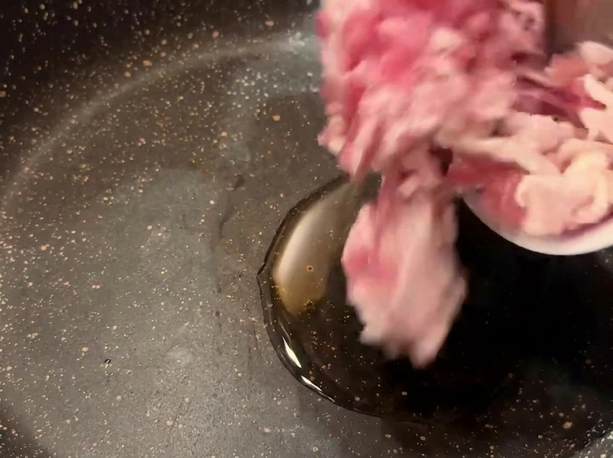 Pezzetti di bacon crudo versati da una ciotolina in una padella calda con olio di semi.