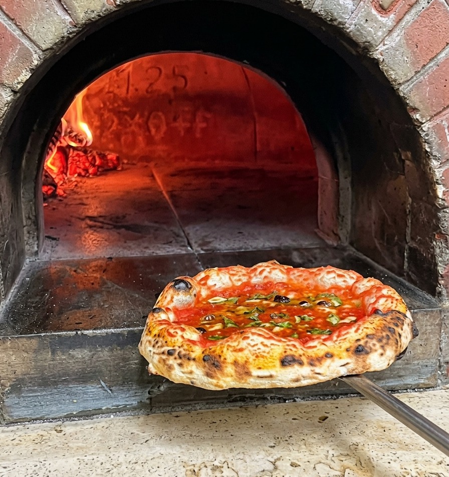 Una pizza napoletana appena cotta con cornicione maculato estratta dal forno a legna su una pala di metallo.
