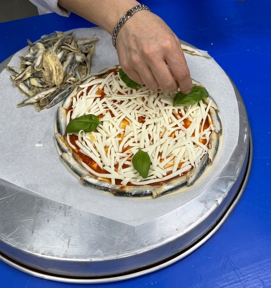 Una mano che posiziona foglie intere di basilico sopra il letto di formaggio bianco grattugiato.