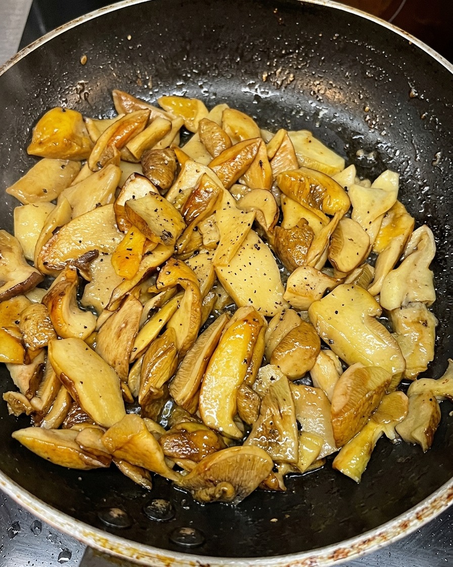 Fette di funghi dorati che rosolano in una padella calda.