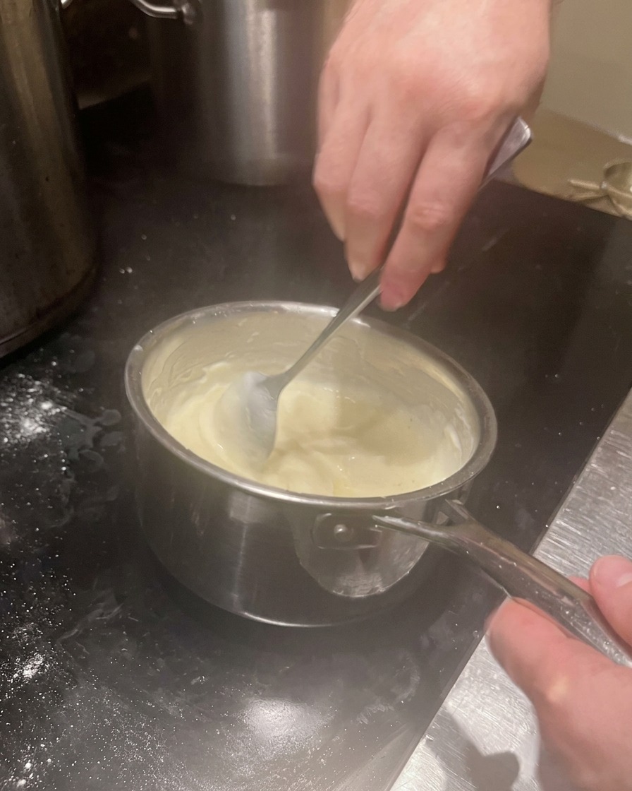 Crema bianca densa mescolata in un pentolino.