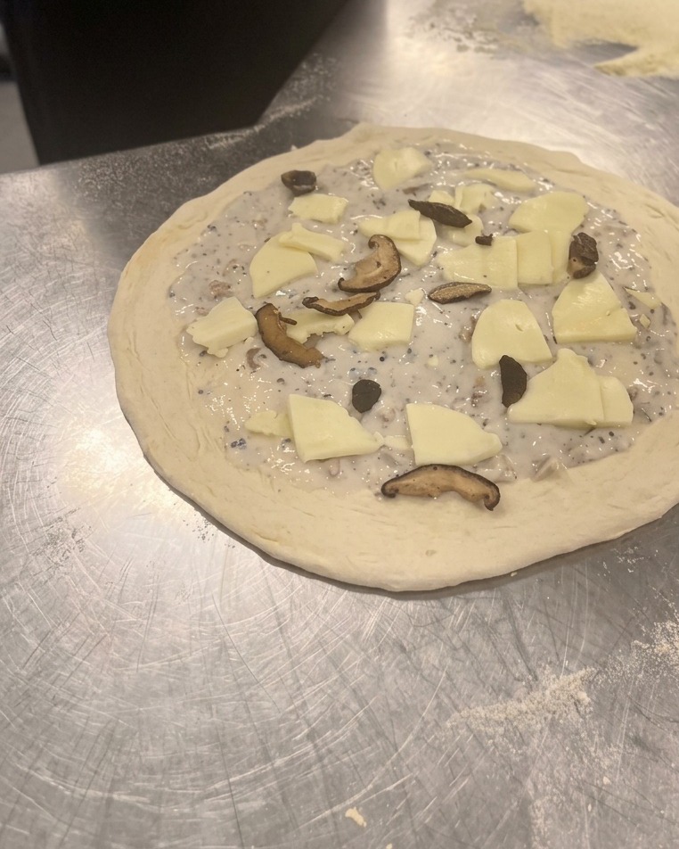 Fette di funghi champignon e shiitake distribuite sulla mozzarella della pizza.