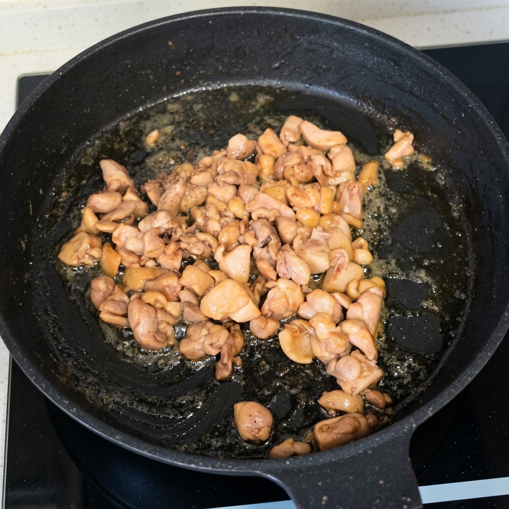 Pollo cotto e dorato che salta in una padella nera.