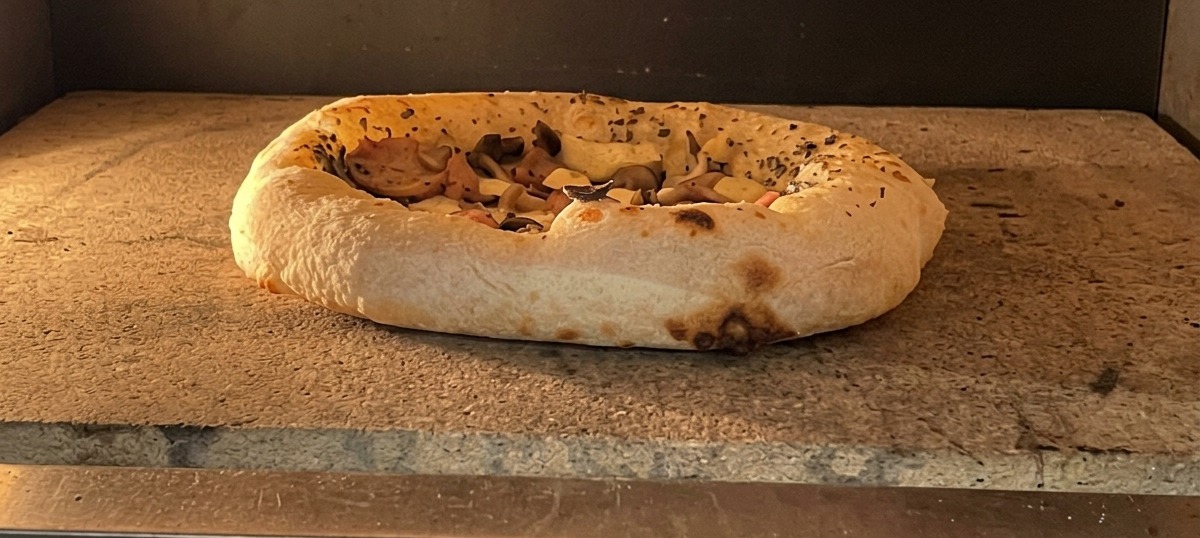 Pizza cotta con cornicione dorato e alveolato pronta per essere servita.