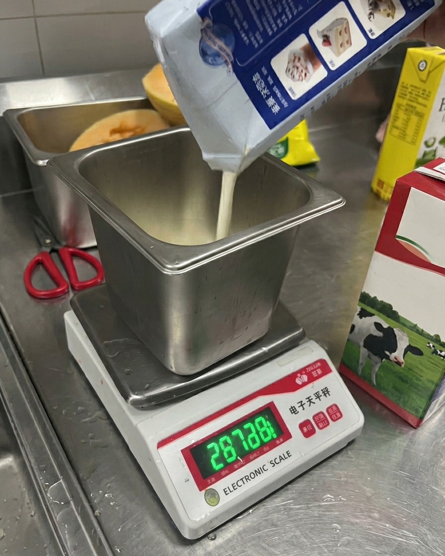 Latte versato da un cartone in un contenitore di metallo posto su una bilancia elettronica digitale.