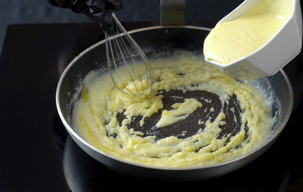Panna fresca versata in una salsa bianca che sobbolle in padella.