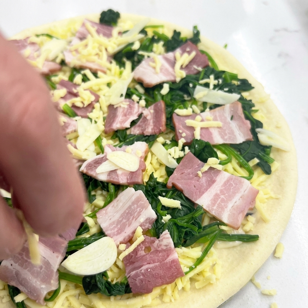 Una mano che spolvera ancora un po di mozzarella sopra la pizza pronta per essere infornata.