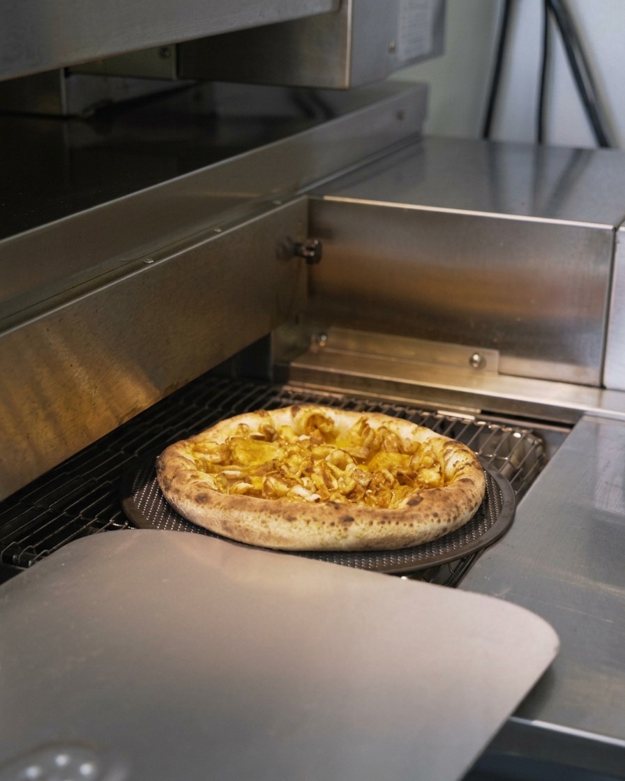 Una pizza ai frutti di mare che scorre in un forno professionale con il bordo che si gonfia e diventa dorato.