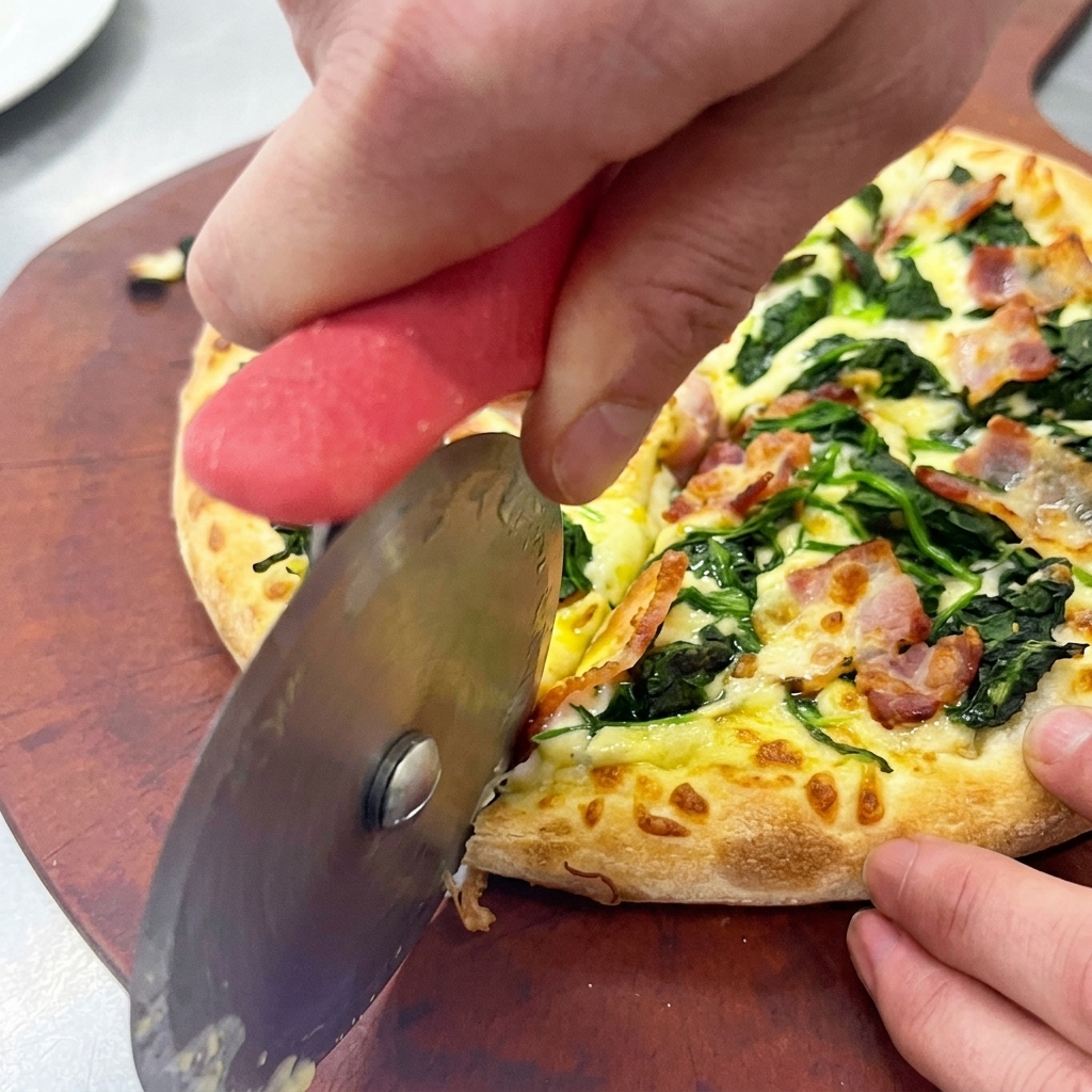 Mani che usano una rotella tagliapizza per dividere la pizza calda su un tagliere di legno.