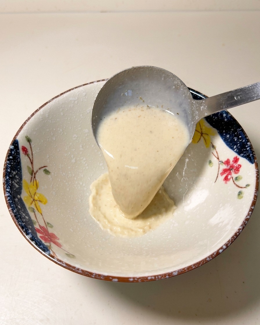 Un mestolo di metallo versa il brodo cremoso e caldo in una ciotola di ceramica decorata.