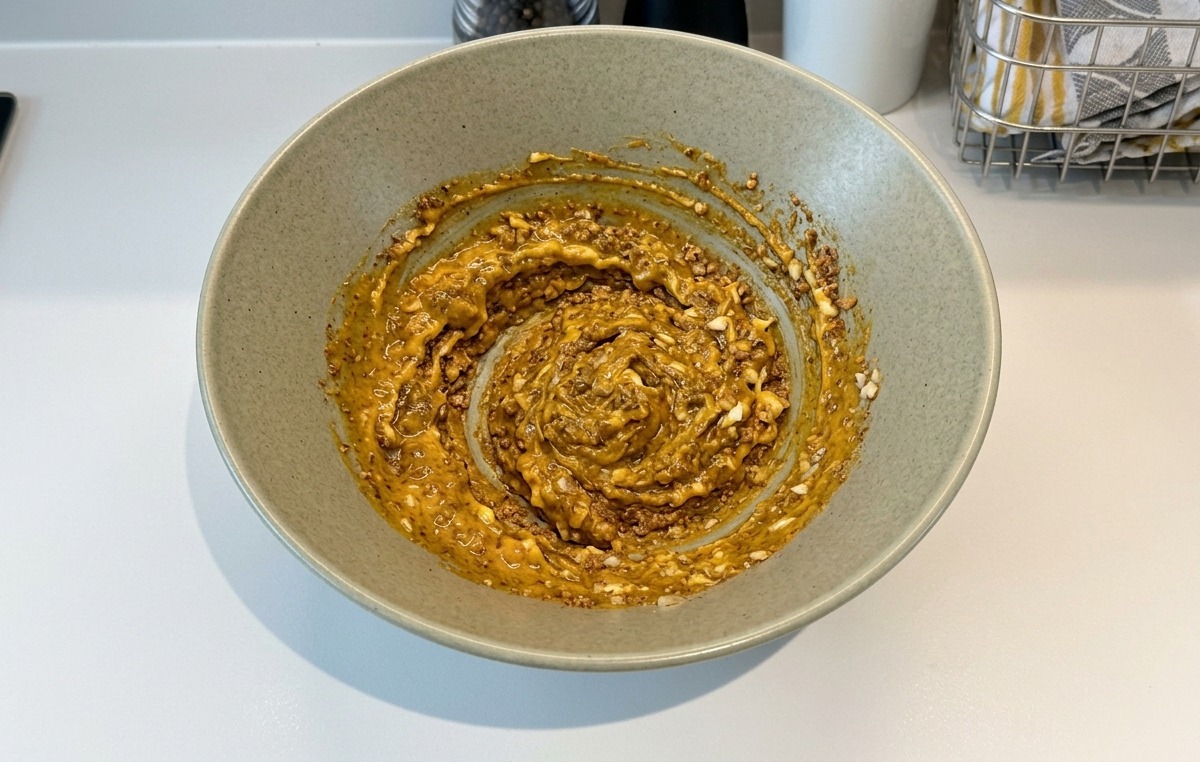 Una pasta densa e marrone ben mescolata allinterno di una ciotola di ceramica.