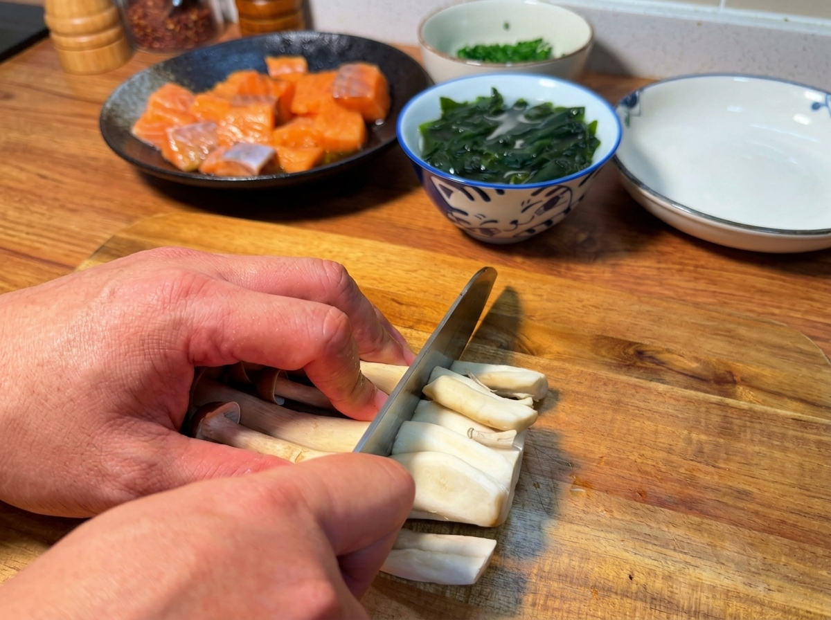 Mani che rimuovono la base dei funghi shimeji marroni su un tagliere di legno.