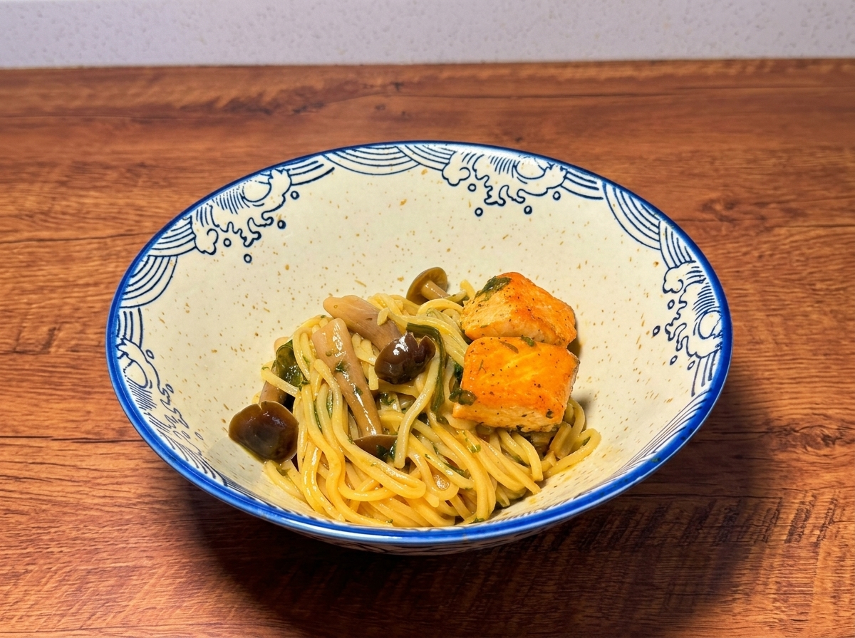Una ciotola di ceramica con noodle guarniti da cubetti di salmone e funghi su una superficie di legno.
