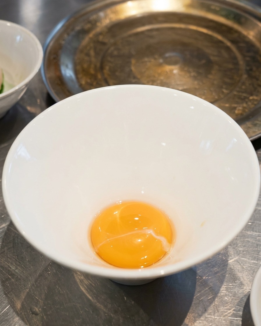 Una piccola quantità di salsa tare dorata sul fondo di una ciotola da ramen in ceramica bianca vuota.