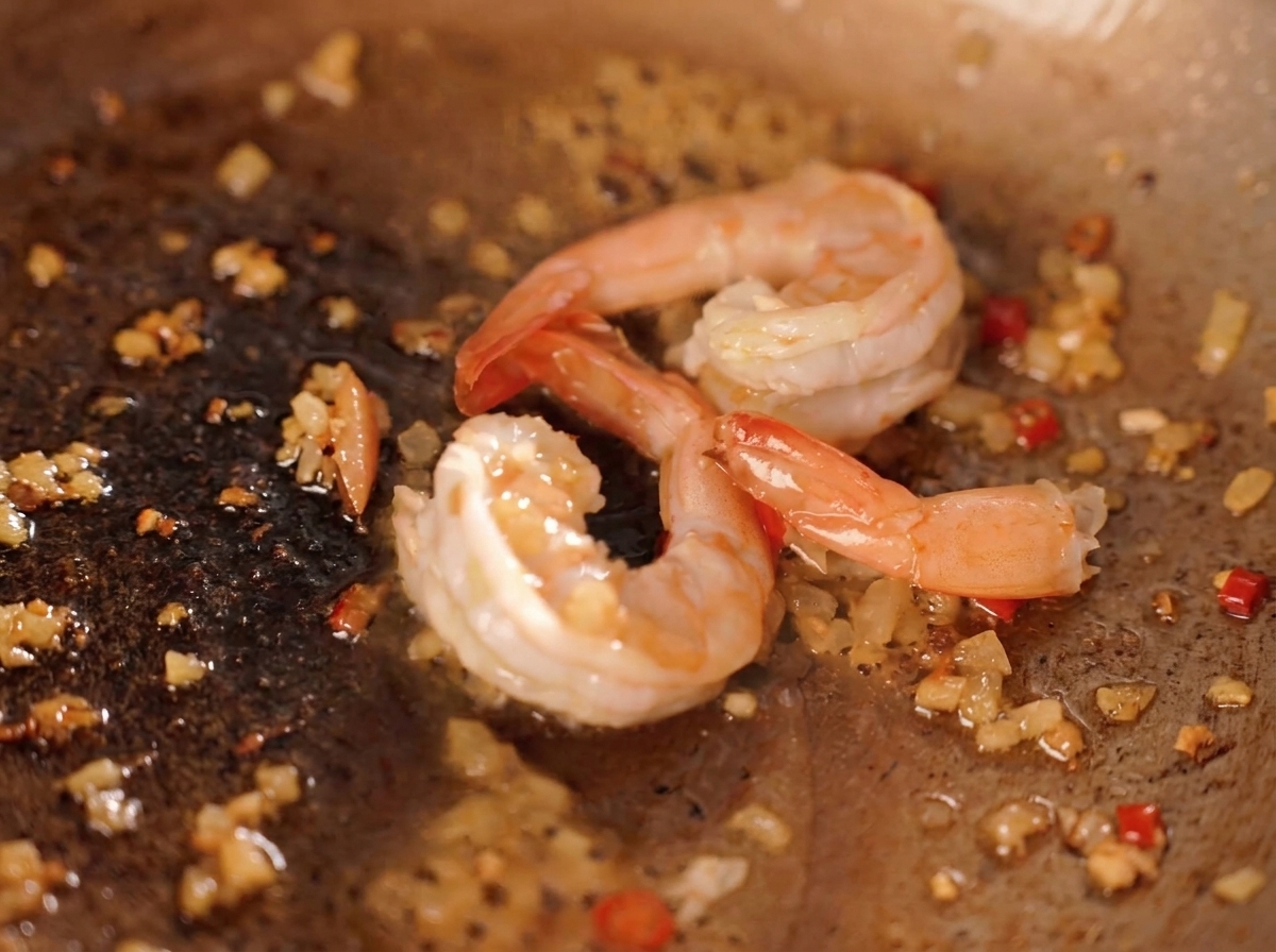 Gamberi saltati in padella con peperoncino tritato, cipolla e briciole di tuorlo duovo salato giallo.