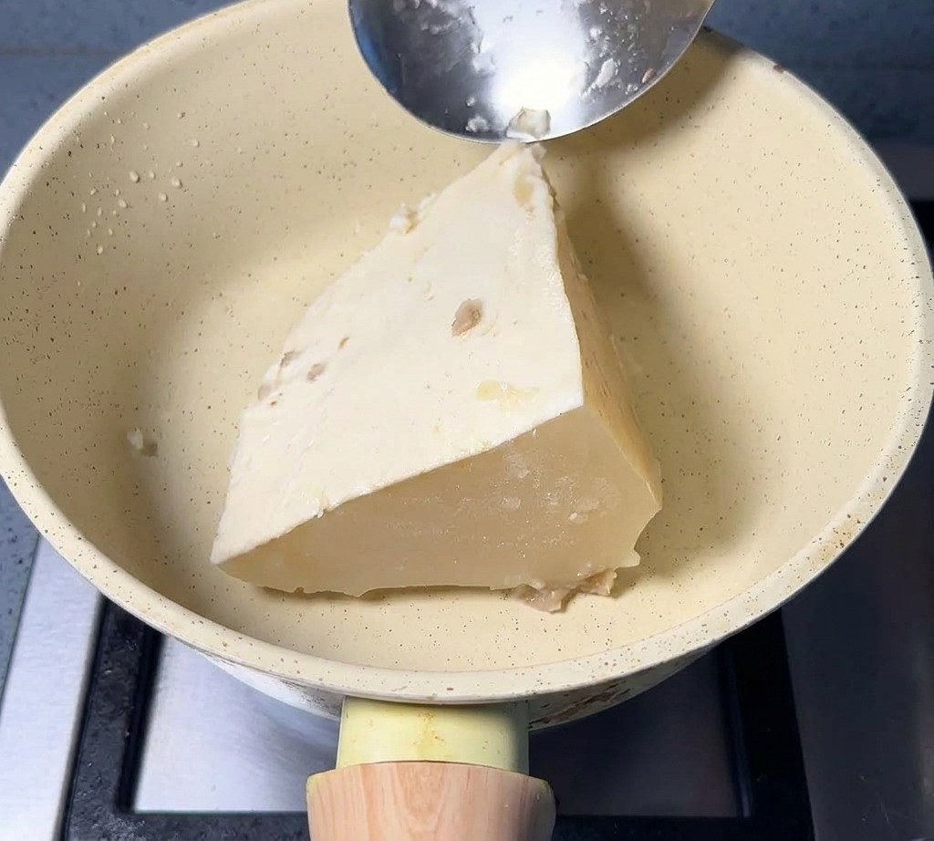 Blocco triangolare di brodo di maiale congelato in una pentola color crema.
