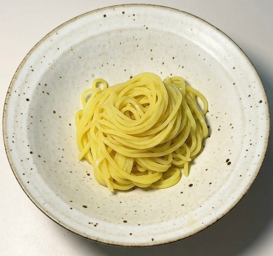 Noodles di ramen gialli disposti con cura in una ciotola di ceramica bianca.