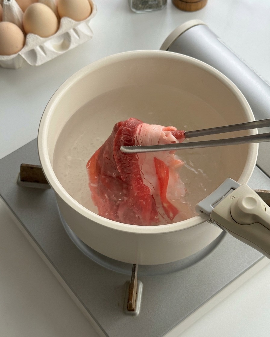 Sottili fettine di manzo crudo sbollentate in una pentola dacqua bollente con le bacchette.
