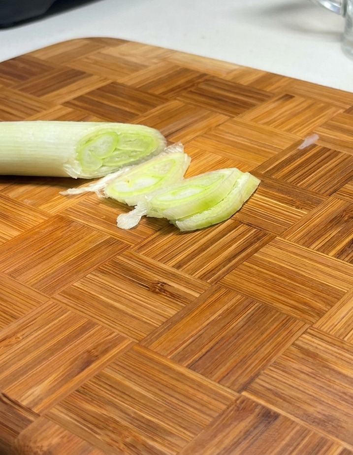 Cipollotti verdi tagliati in diagonale disposti su un tagliere di legno.