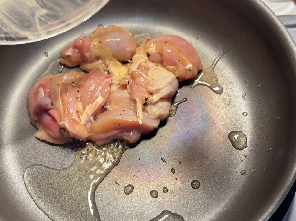 Pezzi di pollo marinati che rosolano in una padella calda con un leggero velo d olio.