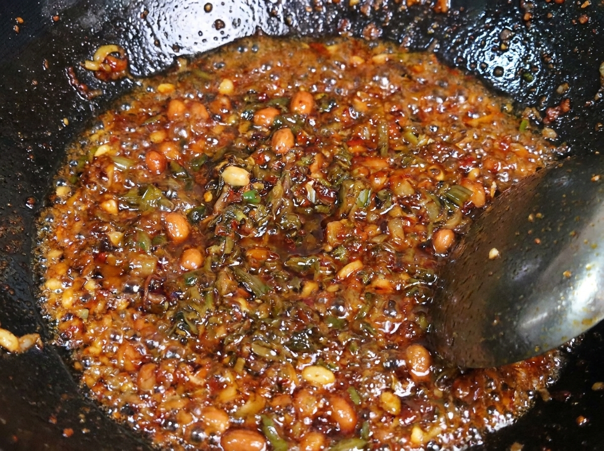 Un mix di maiale macinato condito e germogli Yibin scuri saltati insieme in un wok di metallo caldo.