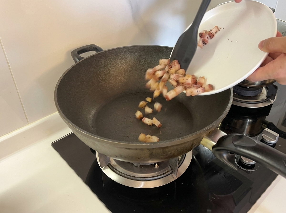 Cubetti di guanciale crudo versati in una padella fredda.
