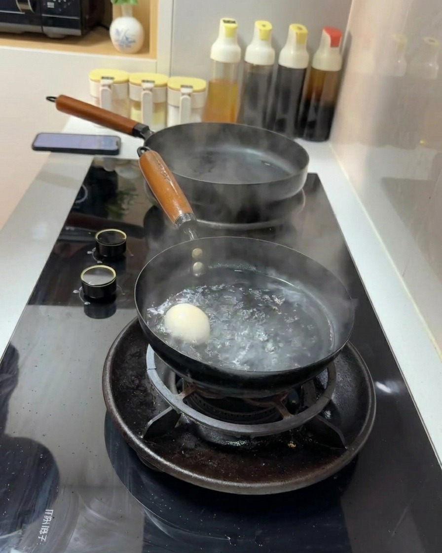 Un uovo bianco immerso in un pentolino dacqua che bolle vivacemente su un fornello a gas.