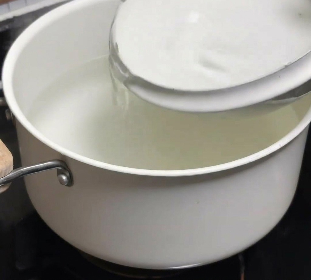 Una ciotola di acqua fredda che viene versata in una pentola di acqua calda appena bollita.