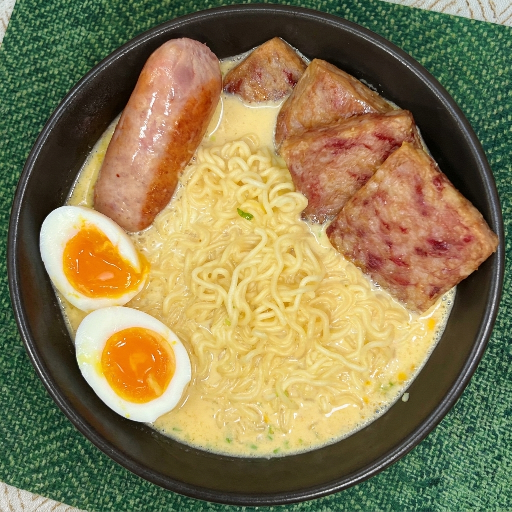 Una ciotola di ramen completa con fette di spam, una salsiccia e due metà di uovo barzotto con tuorlo colante.