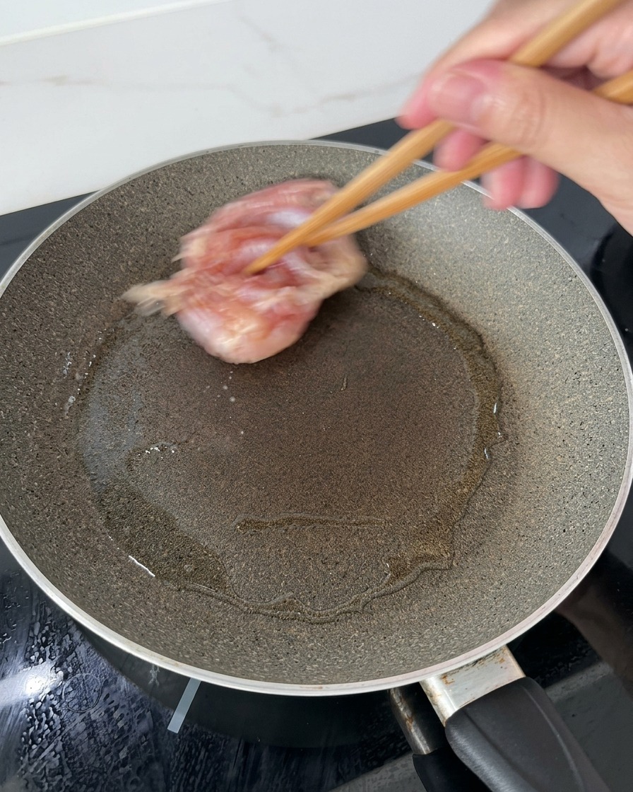 Sovracosce di pollo adagiate in una padella calda e unta dolio usando bacchette di legno, partendo dal lato della pelle.