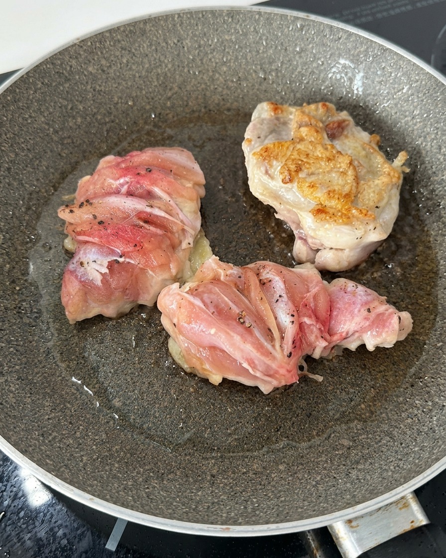 Tre sovracosce di pollo in padella, di cui una girata per mostrare una superficie ben dorata e croccante.