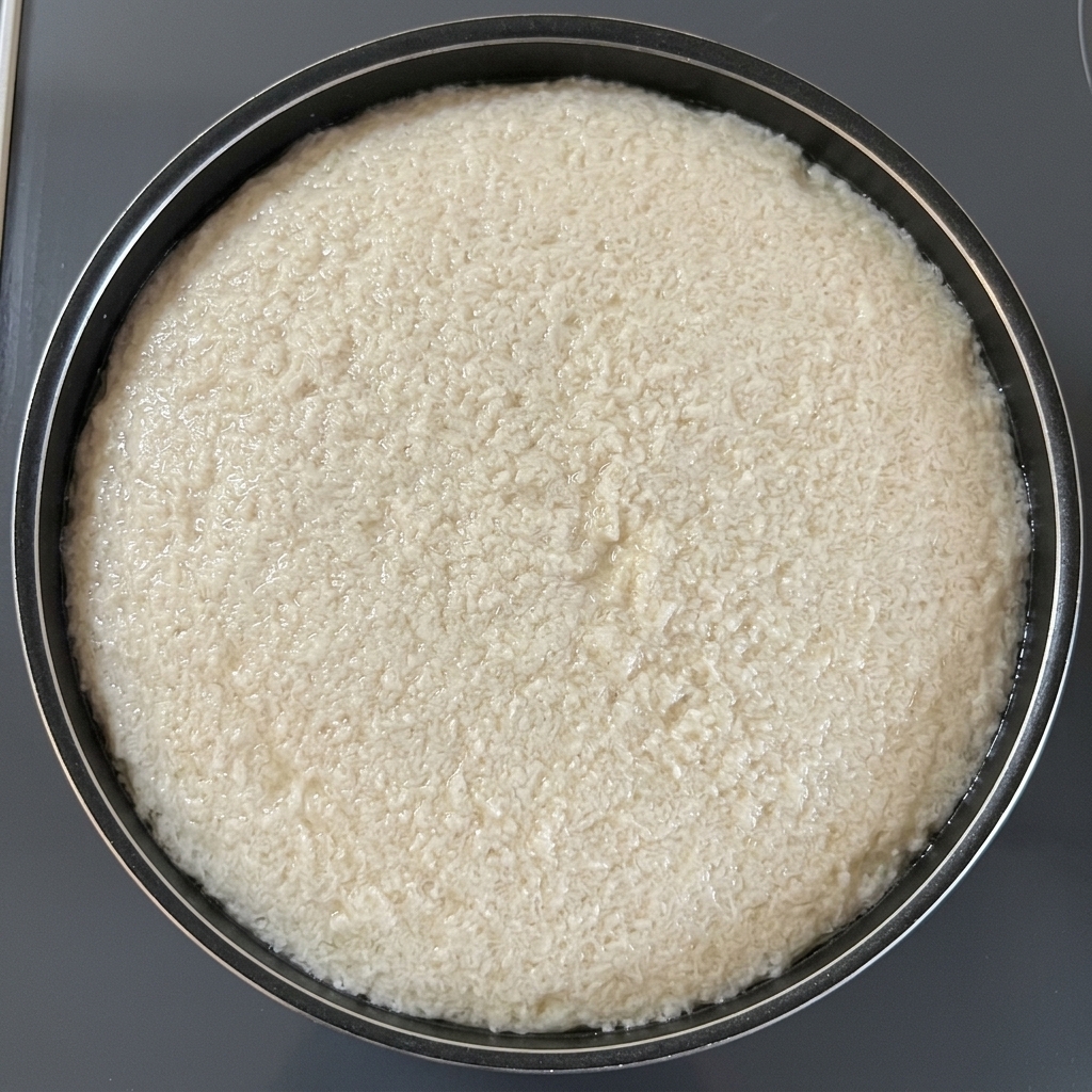 Un foglio circolare di carta assorbente per alimenti che galleggia sullacqua in una pentola nera per rimuovere la schiuma di cottura.