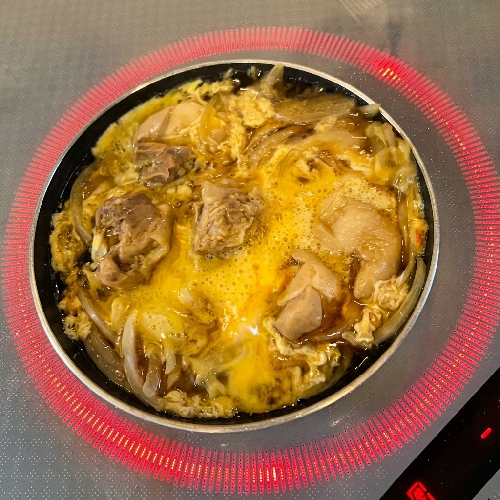 Foglie verdi fresche di mitsuba distribuite sulle uova parzialmente cotte e sul pollo.